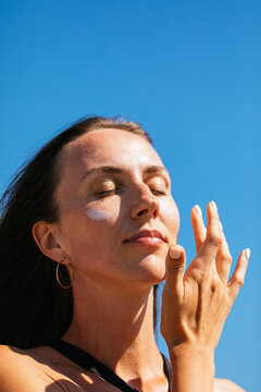 Woman applying sunscreen on her cheeks