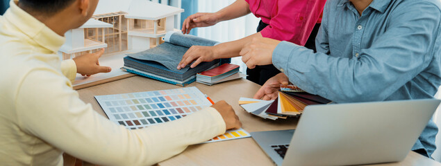 Skilled interior design team carefully selecting curtain materials while coworker selecting the...