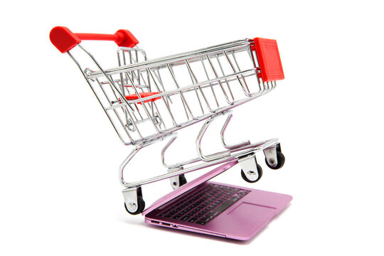 Shopping supermarket cart stands on an open laptop isolated on a white background. Online shopping.