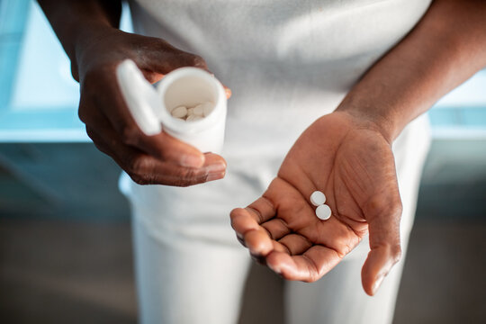 Senior man holding medication tablets and a pill bottle