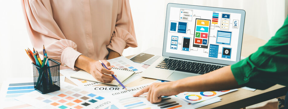 Cropped image of interior designer team recommends color by using color palette while laptop displayed UI and UX designs for mobiles app and website. Creative design and business concept. Variegated.