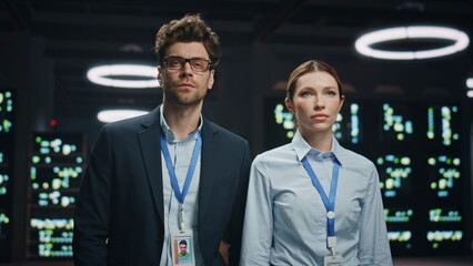 Serious technicians couple posing looking camera in modular datacenter portrait