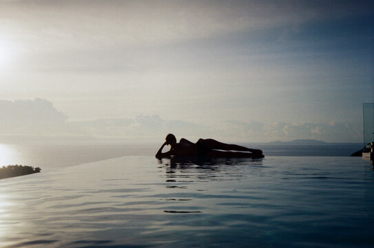 Unrecognizable woman swimming in sea-view luxury infinity pool