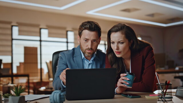 Happy colleagues watching laptop screen cabinet. Cheerful coworkers discussing