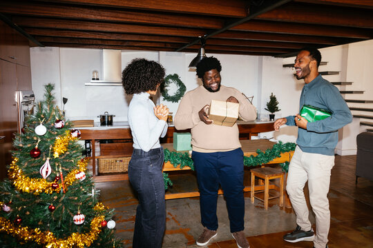 Happy friends opening christmas gifts at home Ugc