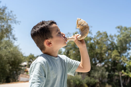 Jewish Child Wearing Kippah Blowing Shofar on Rosh Hashanah Or Kippur.