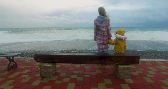 The mother and child are watching the sea from the shore