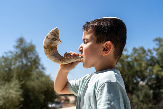 Jewish Child Wearing Kippah Blowing Shofar on Rosh Hashanah Or Kippur.