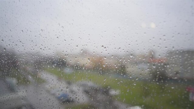 Raindrops glide over windowpane