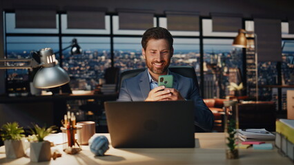 Happy boss relaxing cellphone late office closeup. Positive businessman smiling