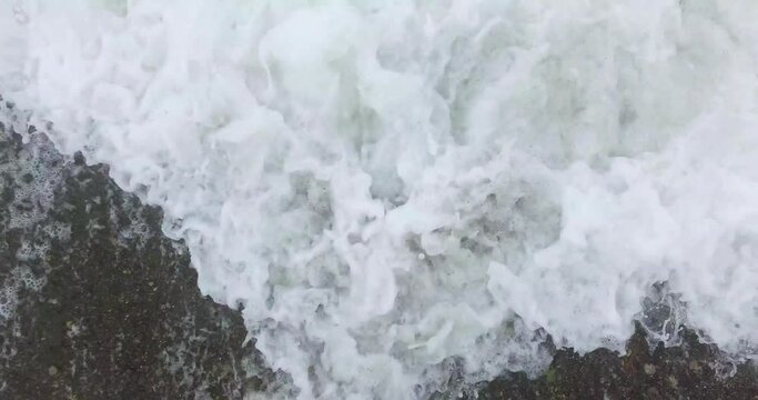 Foamy waves embrace the sea rocks.
