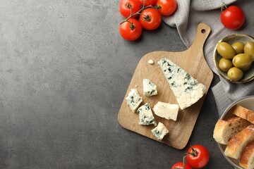 Flat lay composition with wooden cutting board and products on dark textured table. Space for text