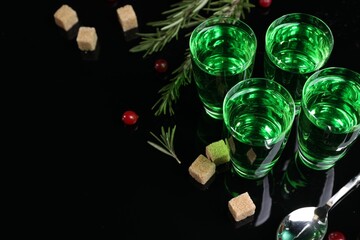 Absinthe in shot glasses, cranberries, rosemary and brown sugar on mirror table, space for text....