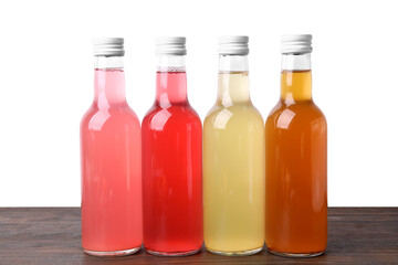 Delicious kombucha in glass bottles on wooden table against white background
