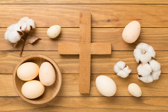 Easter eggs with cross on wooden background, top view