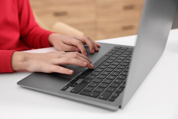 E-learning. Girl using laptop during online lesson at table indoors, closeup