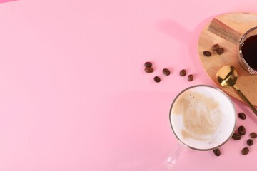 Cup of fresh coffee and beans on pink table, flat lay. Space for text