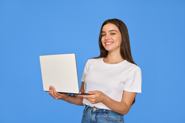 Happy pretty gen z Latin young woman holding laptop, smiling Hispanic student girl with brunette hair using computer elearning online standing isolated on blue background looking at camera.