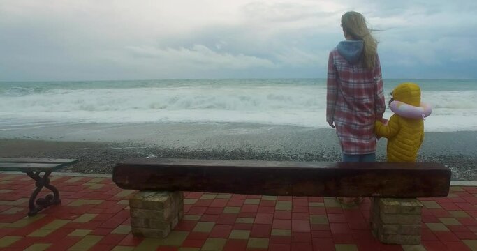 The mother and child are watching the sea from the shore