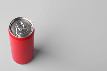 Energy drink in red can on light grey background, space for text