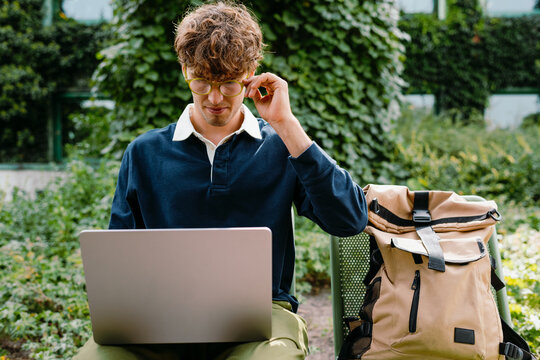A man uses a laptop sitting outdoors