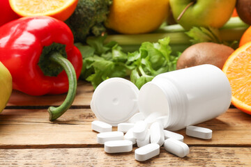 Dietary supplements. Overturned bottle, pills and food products on wooden table