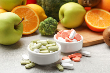 Dietary supplements. Different pills in bowls and food products on grey table