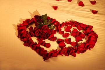 Honeymoon. Heart made with roses and beautiful petals on bed