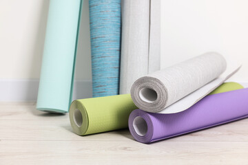Different wallpaper rolls near white wall indoors