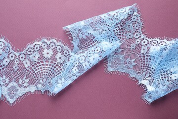 White lace on purple background, top view