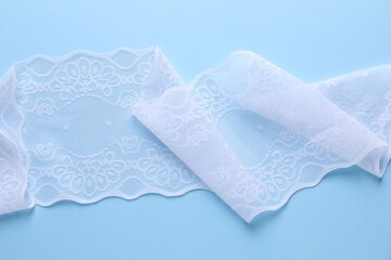 White lace on light blue background, top view