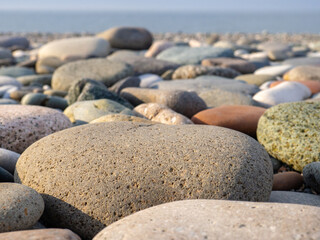 Gray sand and stones close-up on the beach. Stone in the foreground. Beach in winter. Sea coast soil