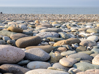 Gray sand and stones close-up on the beach. Stone in the foreground. Beach in winter. Sea coast soil