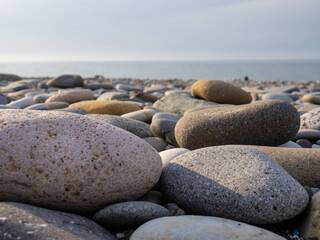 Gray sand and stones close-up on the beach. Stone in the foreground. Beach in winter. Sea coast soil.