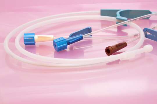 Medical background: Parts of triple lumen short-term central venous catheter set with infusion channels and Seldinger guidewire on rose background