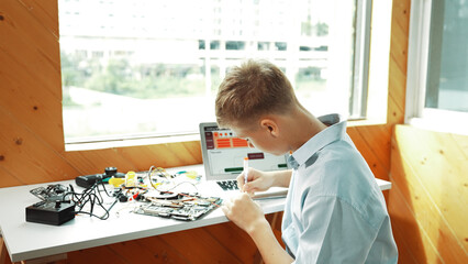 Back view of smart adult repair main board by using electronic equipment on table with laptop with...
