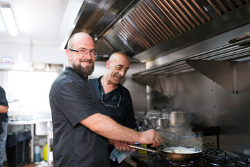 Smiling chefs cooking together at restaurant
