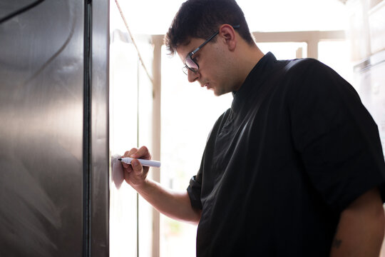 Chef writing needed ingredients on kitchen list