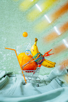 A set with a grocery basket and fruit.