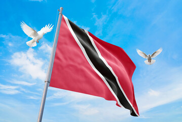 Waving flag of Trinidad and Tobago in beautiful sky and flying pigeons. Trinidad and Tobago flag...