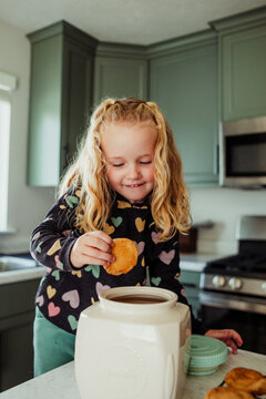 Child takes pulls the cookie out of a jar.