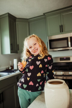 Child smiles for the camera with her cookie in hand.