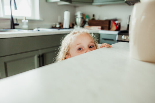 Child peeks over the edge of the kitchen counter.