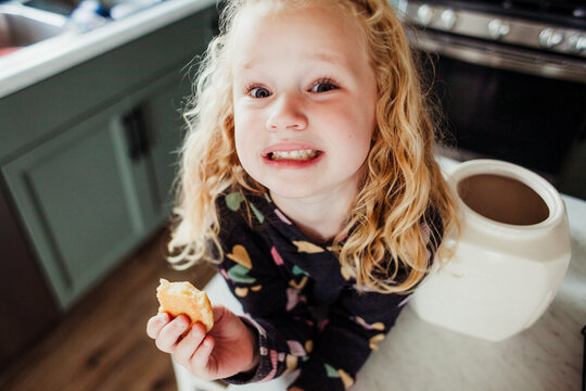 Child smiles for the camera with her cookie in hand birdseye.