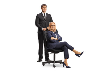 Young businessman standing behind a woman boss sitting in an office chair