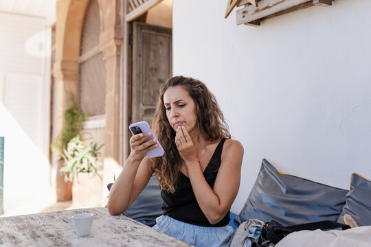 Contemplative woman holding smartphone, planning travel.
