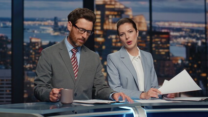 Serious hosts broadcasting news late studio closeup. Couple newscasters talking - obrazy, fototapety, plakaty