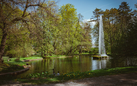Teich mit Springbrunnen im Park mit großen Bäumen - romantischer Springbrunnen