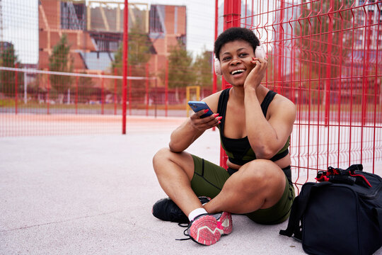 Ebony fitness model listening to music after workout