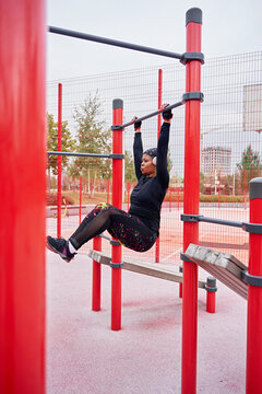 Black female athlete pulls up on parallel bars